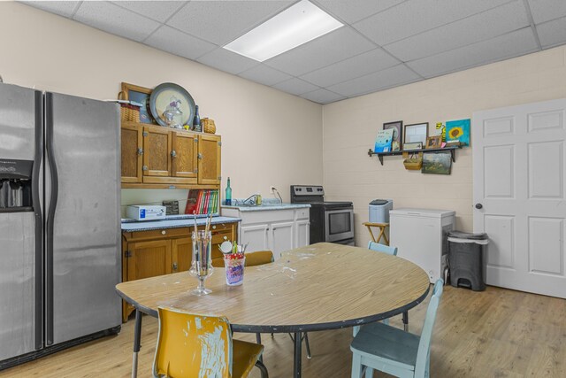 kitchen featuring stainless steel appliances, light wood-type flooring, white cabinetry, and a paneled ceiling