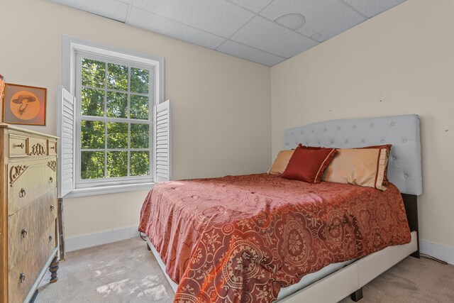 bedroom with light colored carpet and a paneled ceiling