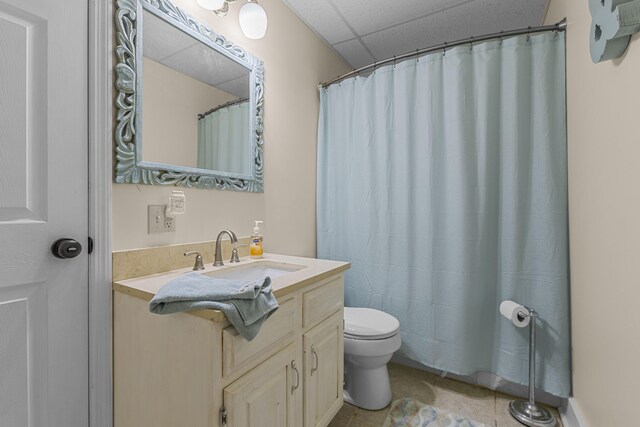 bathroom with vanity, a paneled ceiling, toilet, and tile patterned flooring