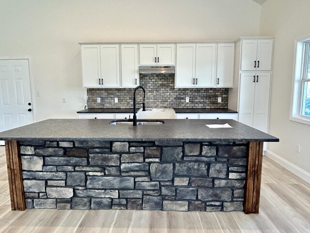 kitchen featuring an island with sink, sink, white cabinetry, and light hardwood / wood-style floors