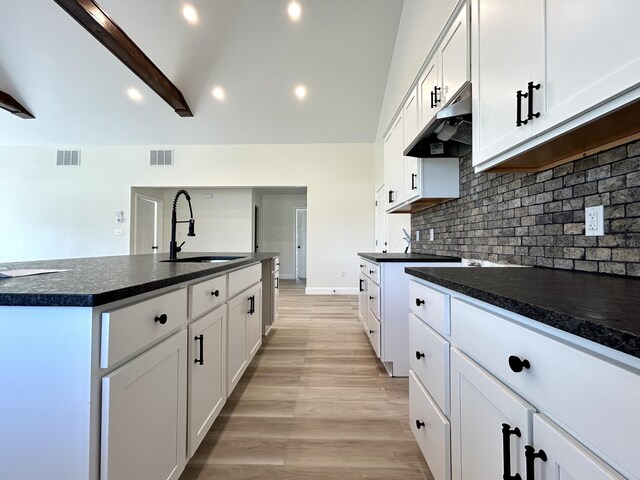 kitchen featuring a kitchen island with sink, light wood-type flooring, sink, and white cabinets