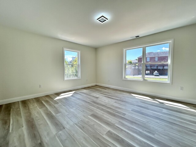 empty room with light hardwood / wood-style flooring and a healthy amount of sunlight