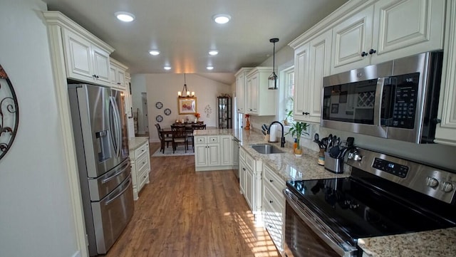 kitchen featuring sink, decorative light fixtures, white cabinetry, hardwood / wood-style flooring, and appliances with stainless steel finishes