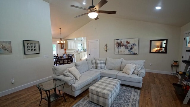 living room with ceiling fan with notable chandelier, dark wood-type flooring, and high vaulted ceiling