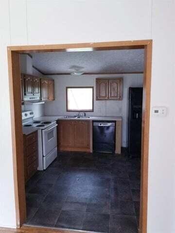 kitchen featuring a textured ceiling, dishwasher, sink, and white range with electric stovetop