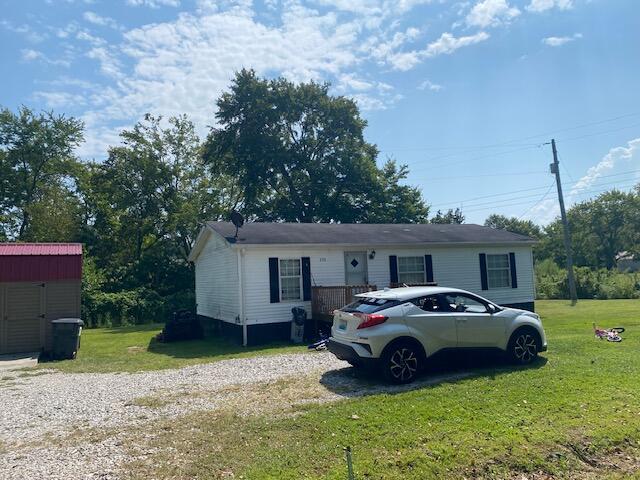 ranch-style home with a storage shed and a front lawn