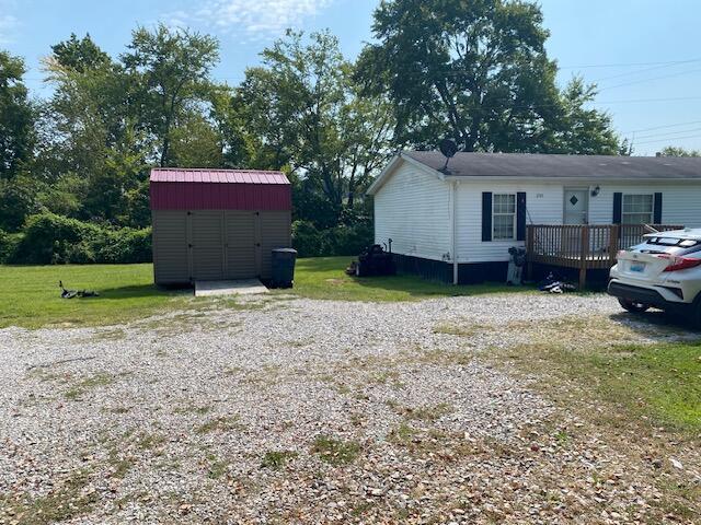 exterior space featuring a storage shed, a yard, and a wooden deck