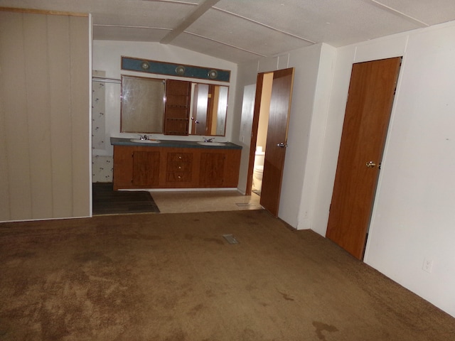 unfurnished room featuring carpet, lofted ceiling, and sink