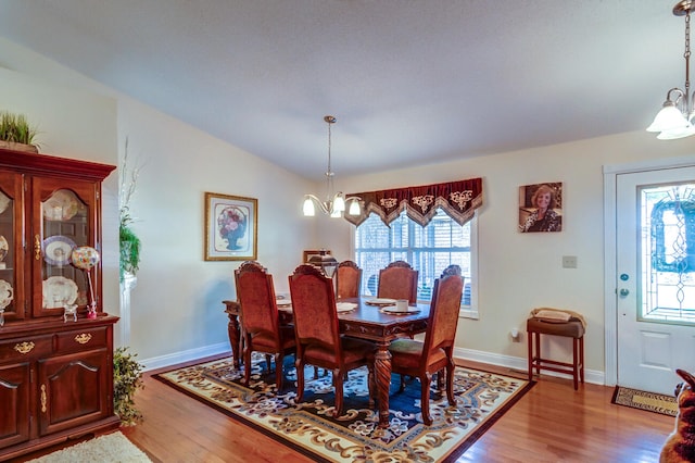 dining room featuring light hardwood / wood-style flooring, a chandelier, and vaulted ceiling