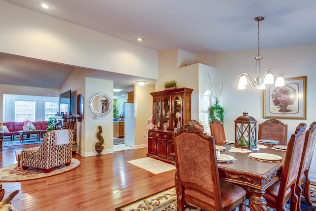 dining room featuring lofted ceiling, wood-type flooring, and a chandelier