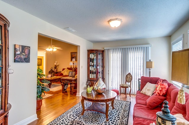 living room featuring ceiling fan, wood-type flooring, and a textured ceiling