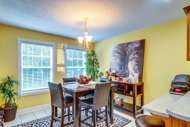 tiled dining room with a chandelier and a textured ceiling