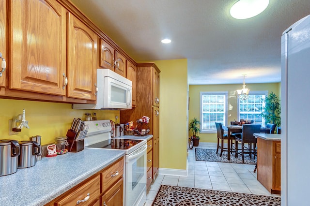 kitchen featuring decorative light fixtures, white appliances, light tile patterned floors, and a chandelier