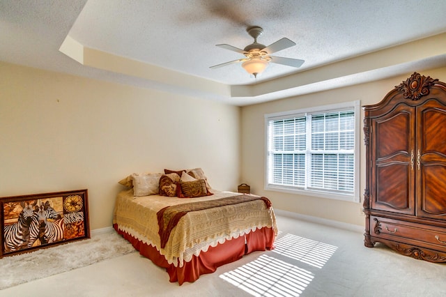 carpeted bedroom featuring ceiling fan and a tray ceiling