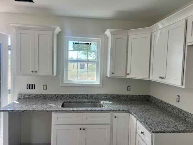 kitchen featuring white cabinets, sink, and dark stone countertops