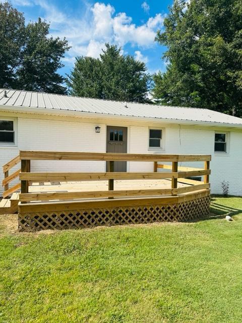 back of property featuring a wooden deck and a lawn