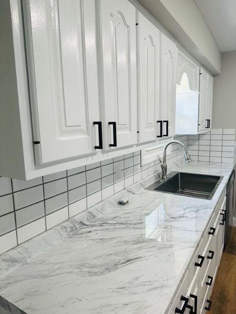 kitchen with hardwood / wood-style flooring, sink, decorative backsplash, and white cabinetry