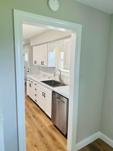 kitchen with dishwasher, sink, light wood-type flooring, and tasteful backsplash