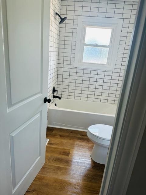 bathroom with toilet, hardwood / wood-style floors, and tiled shower / bath