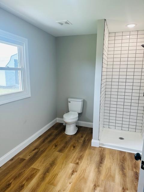 bathroom featuring toilet, hardwood / wood-style flooring, and walk in shower