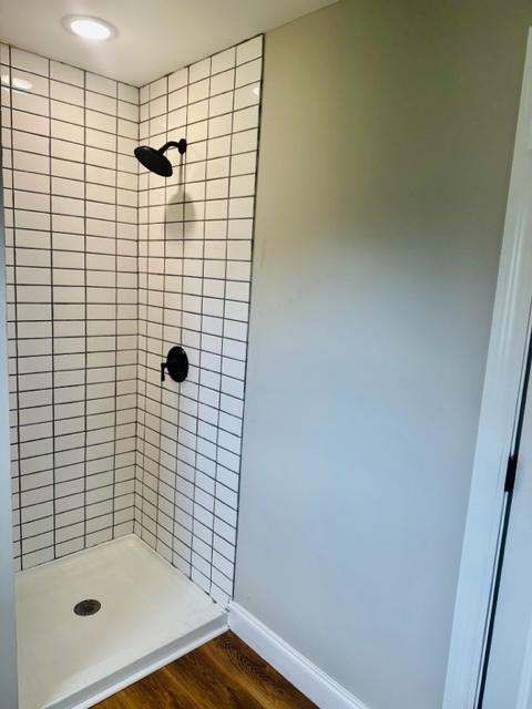 bathroom featuring tiled shower and wood-type flooring