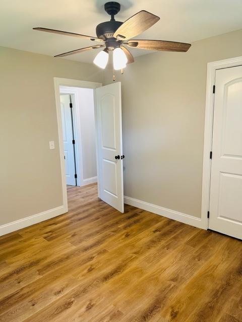 empty room with ceiling fan and light hardwood / wood-style floors