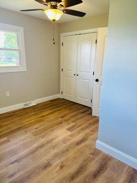 unfurnished bedroom with hardwood / wood-style floors, ceiling fan, and a closet