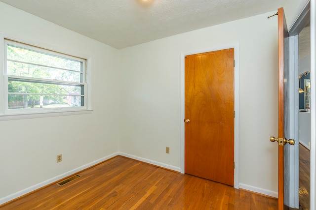 unfurnished bedroom with hardwood / wood-style flooring and a textured ceiling