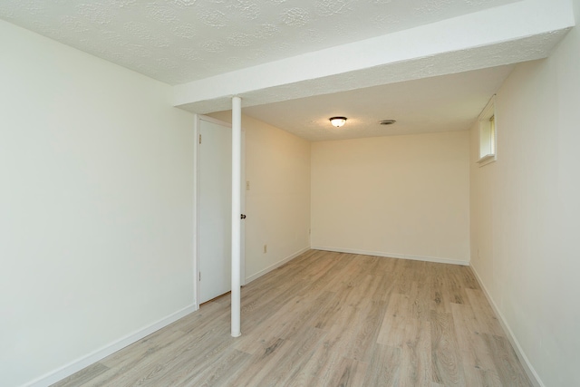 unfurnished room with a textured ceiling and light hardwood / wood-style floors