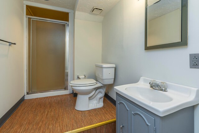 bathroom featuring a textured ceiling, vanity, hardwood / wood-style floors, walk in shower, and toilet