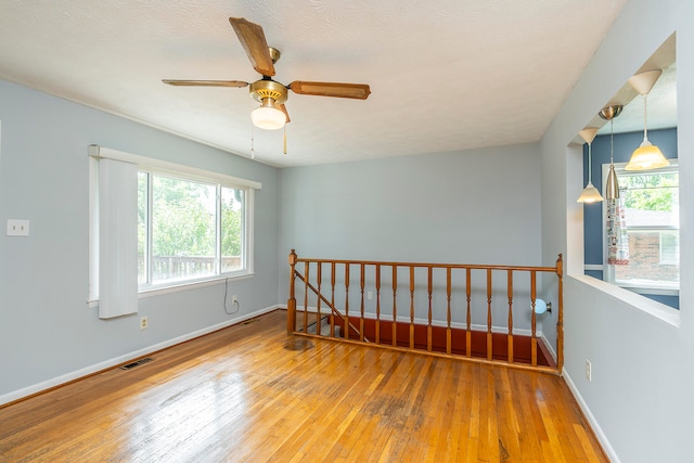 unfurnished room featuring ceiling fan, a wealth of natural light, a textured ceiling, and light hardwood / wood-style flooring