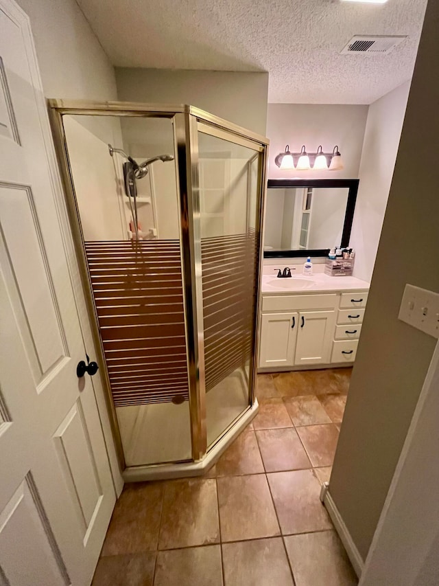 bathroom featuring vanity, an enclosed shower, a textured ceiling, and tile patterned floors