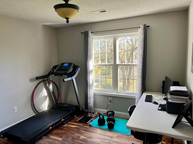 exercise area with a healthy amount of sunlight, wood-type flooring, and a textured ceiling