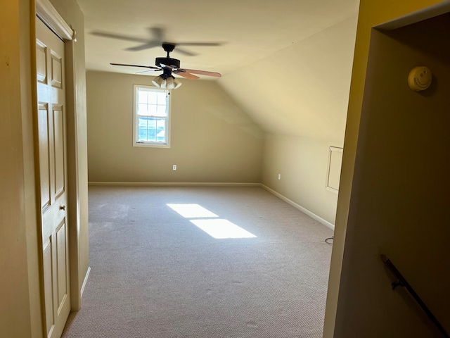 additional living space with vaulted ceiling, light colored carpet, and ceiling fan