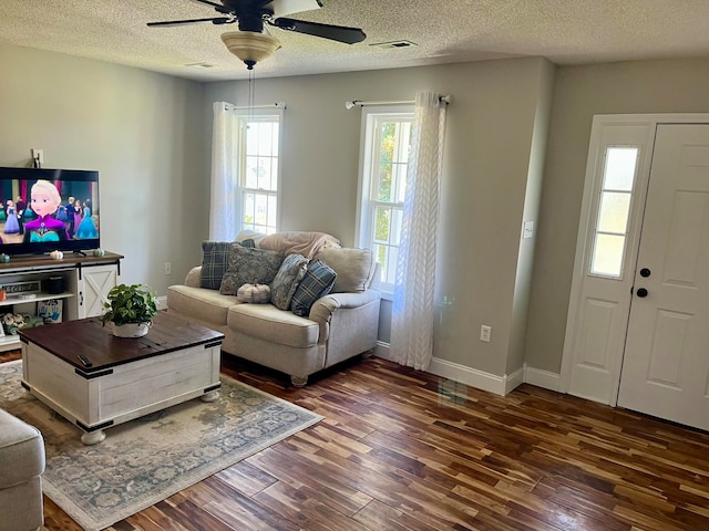 living room with ceiling fan, a textured ceiling, and dark hardwood / wood-style flooring