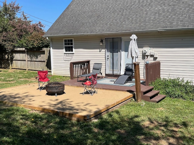 back of property featuring an outdoor fire pit, a deck, and a lawn