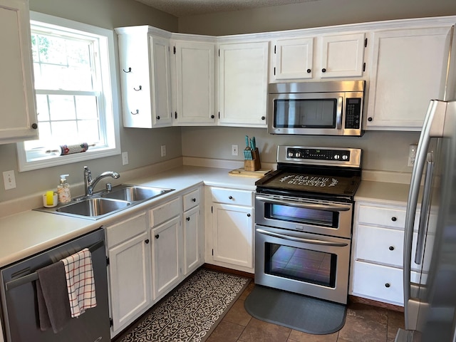 kitchen featuring white cabinetry, a textured ceiling, dark tile patterned floors, sink, and stainless steel appliances