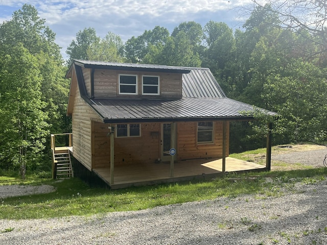 view of front of house featuring a deck, metal roof, stairs, and a wooded view