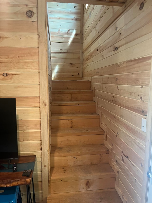 staircase featuring wood walls