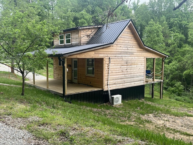 view of side of home featuring a deck, a wooded view, and ac unit