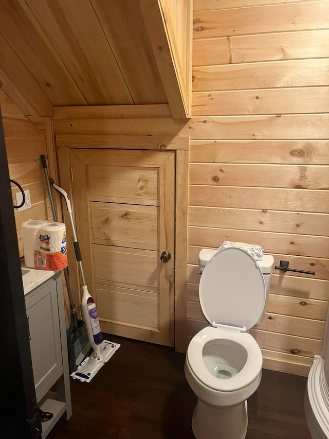 bathroom with toilet, hardwood / wood-style flooring, and wooden walls