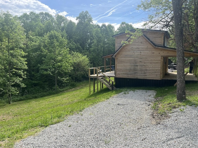 view of side of property featuring a deck, a forest view, and faux log siding