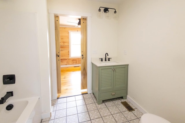 bathroom featuring ceiling fan, tile patterned flooring, wood walls, toilet, and vanity