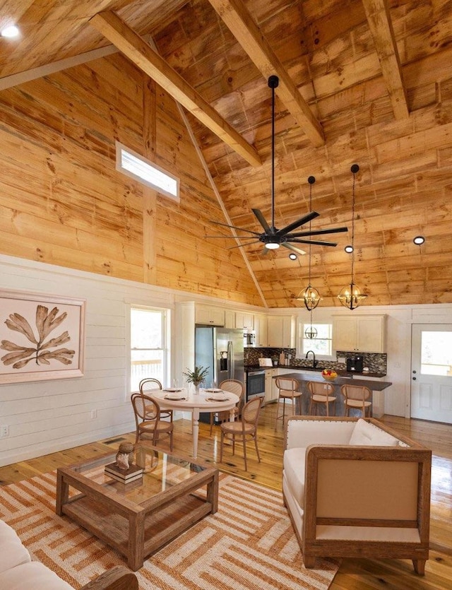 living room featuring light hardwood / wood-style flooring, high vaulted ceiling, plenty of natural light, and wooden walls