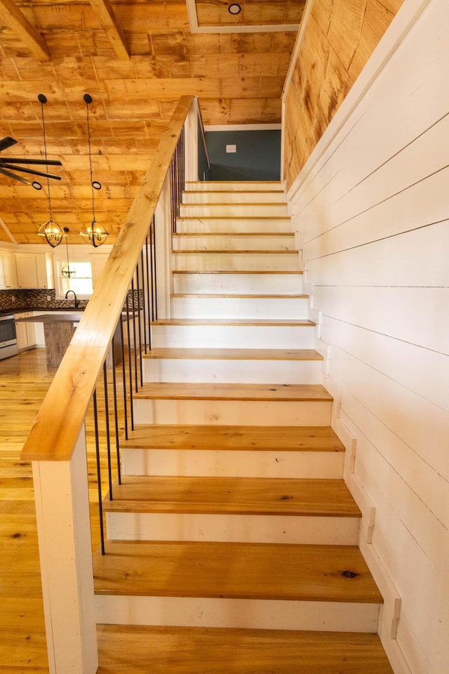 stairs featuring hardwood / wood-style floors, wooden ceiling, and wooden walls