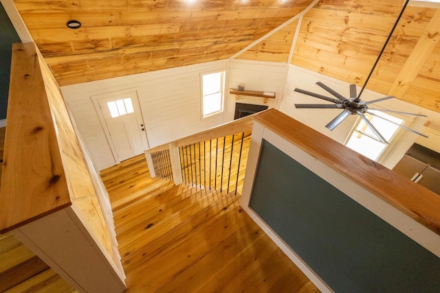 staircase with wood walls, hardwood / wood-style floors, wood ceiling, and vaulted ceiling