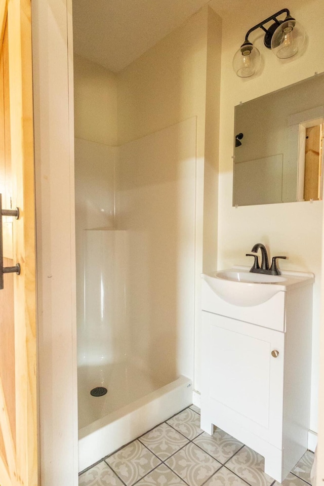 bathroom with tile patterned floors, a shower, and vanity