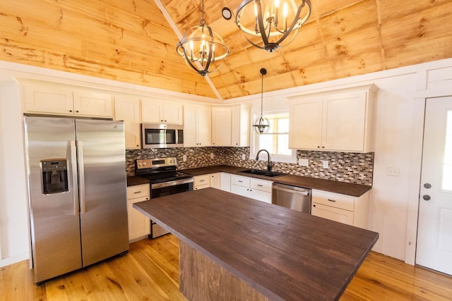 kitchen featuring stainless steel appliances, sink, decorative light fixtures, light hardwood / wood-style flooring, and a chandelier