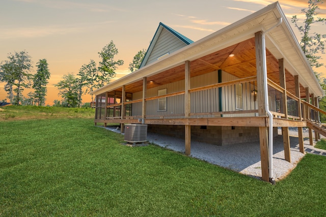 property exterior at dusk featuring a yard and central AC unit