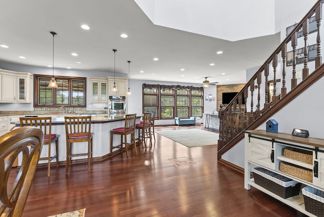 interior space featuring stone counters, pendant lighting, a breakfast bar area, and dark hardwood / wood-style flooring